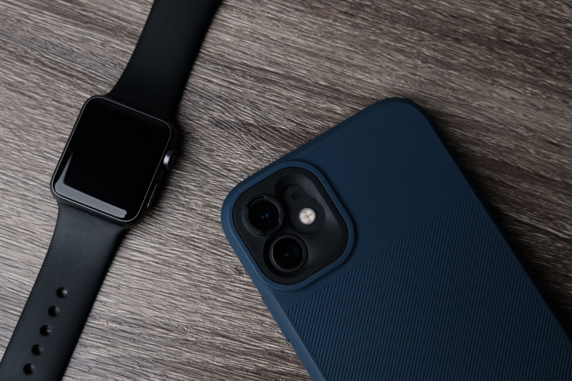 Smartwatch e smartphone lado a lado sobre uma mesa de madeira